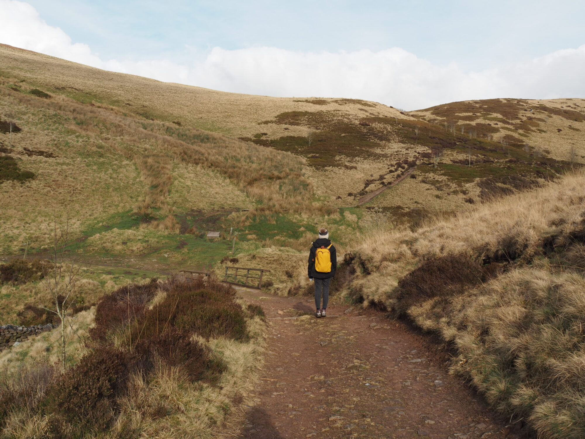 Hiker on a walking trail through open moorland hills in the Peak District